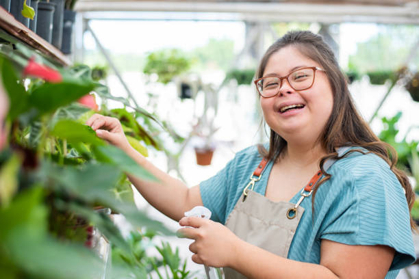 Jovem com síndrome de Down cuidando de plantas em estufa, em atividade de horticultura