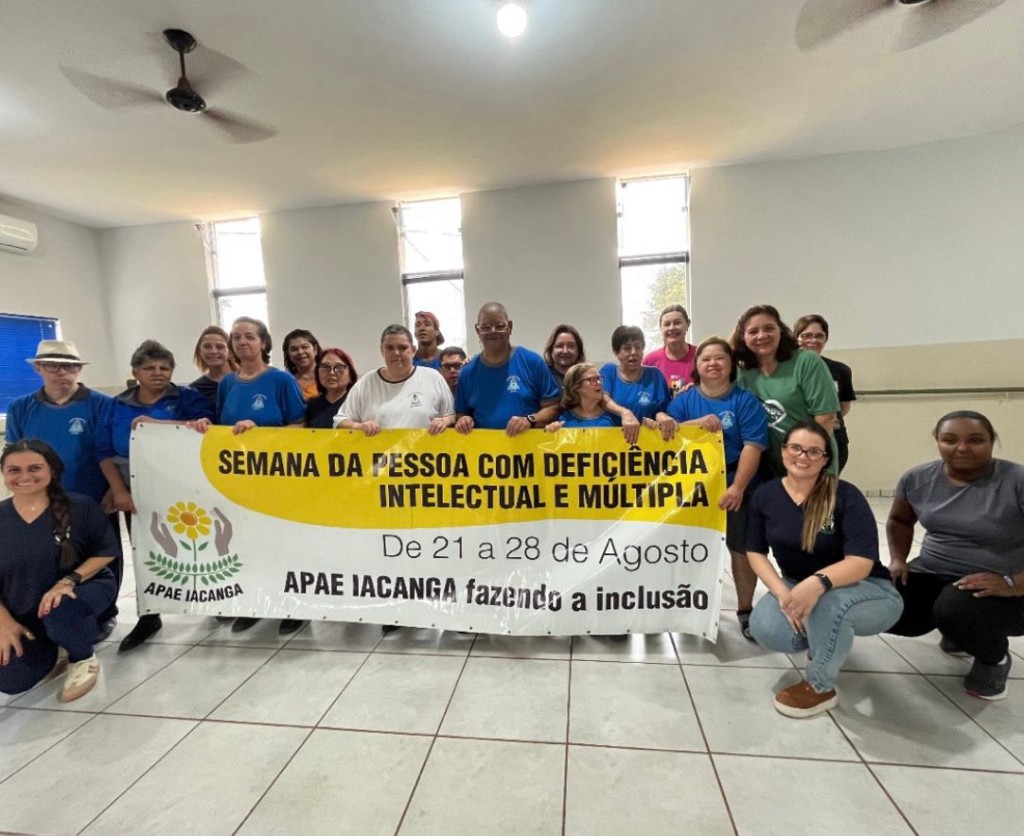 Equipe e participantes da APAE de Iacanga com camisetas azuis e faixa institucional de inclusão