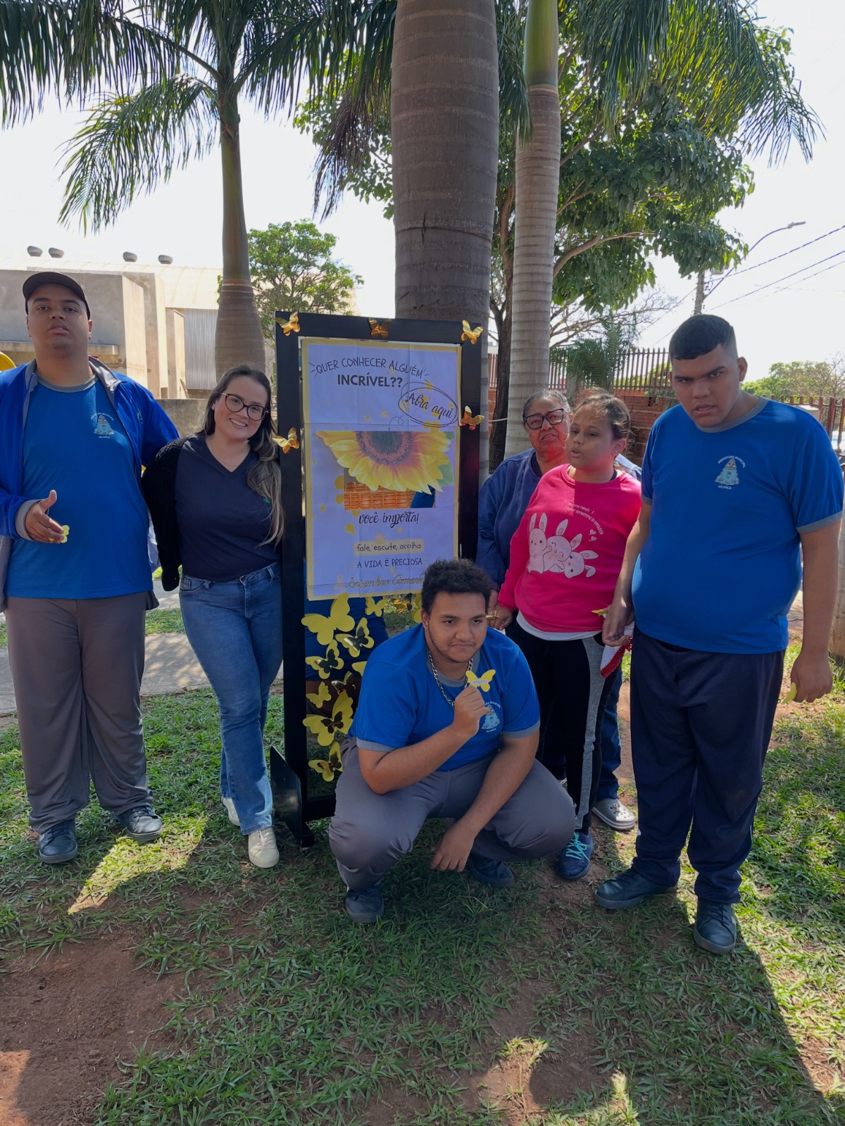 Participantes e equipe da APAE de Iacanga junto ao painel do Setembro Amarelo