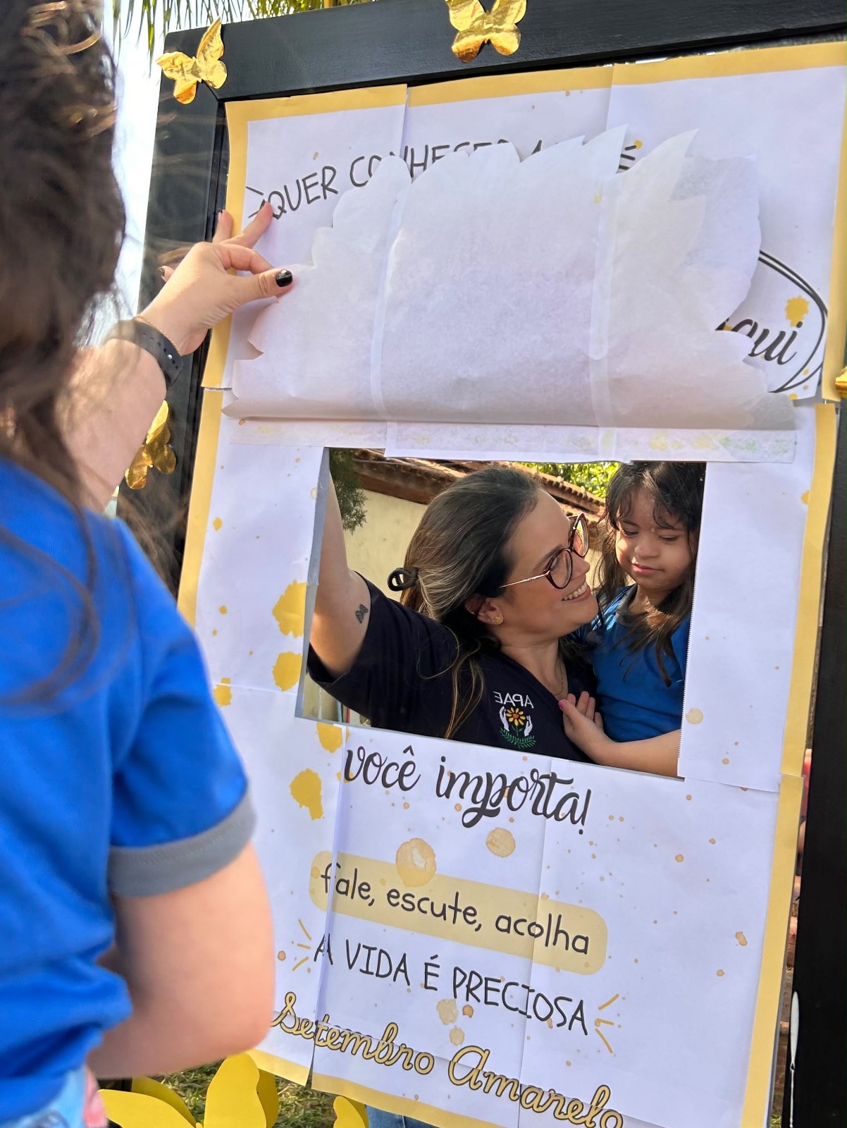 Colaboradora e criança da APAE de Iacanga no painel “você importa!” do Setembro Amarelo